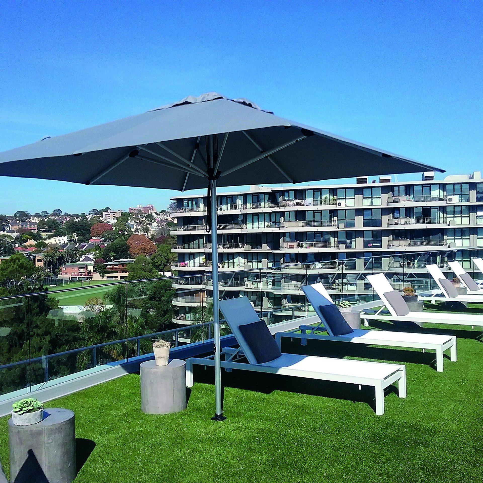 Square umbrella open on a roof top area with deck chairs