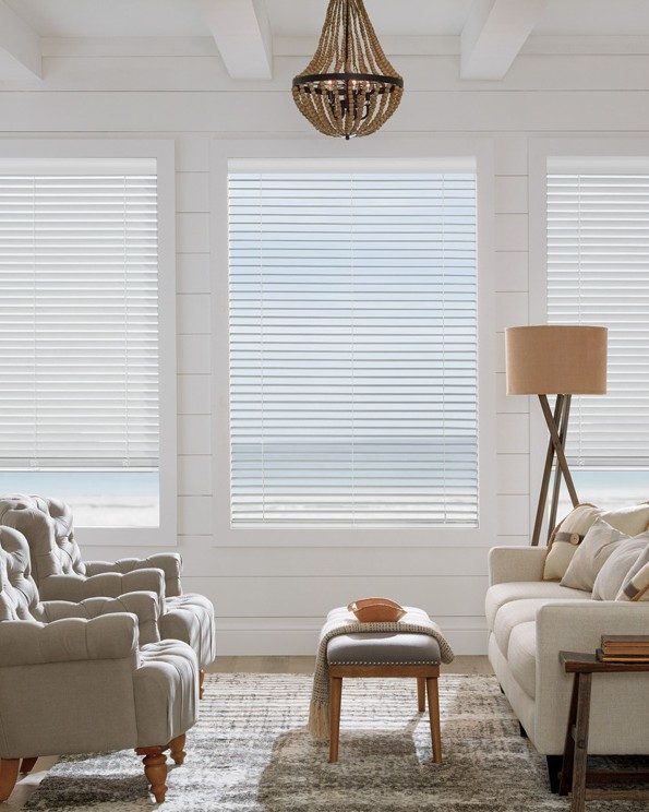 three white timber blinds over windows looking out over water