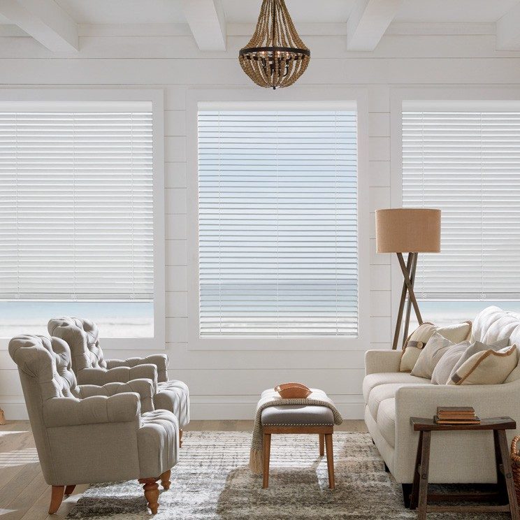 three white timber blinds over windows looking out over water