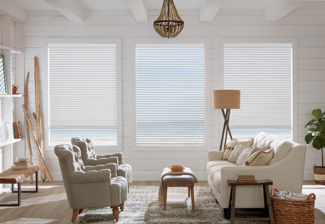 three white timber blinds over windows looking out over water