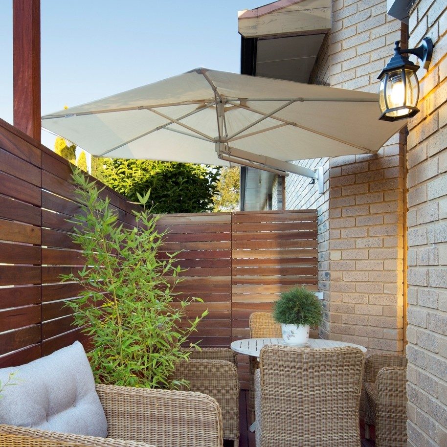 hexagon umbrella with pivot arm attached to brick wall over a deck
