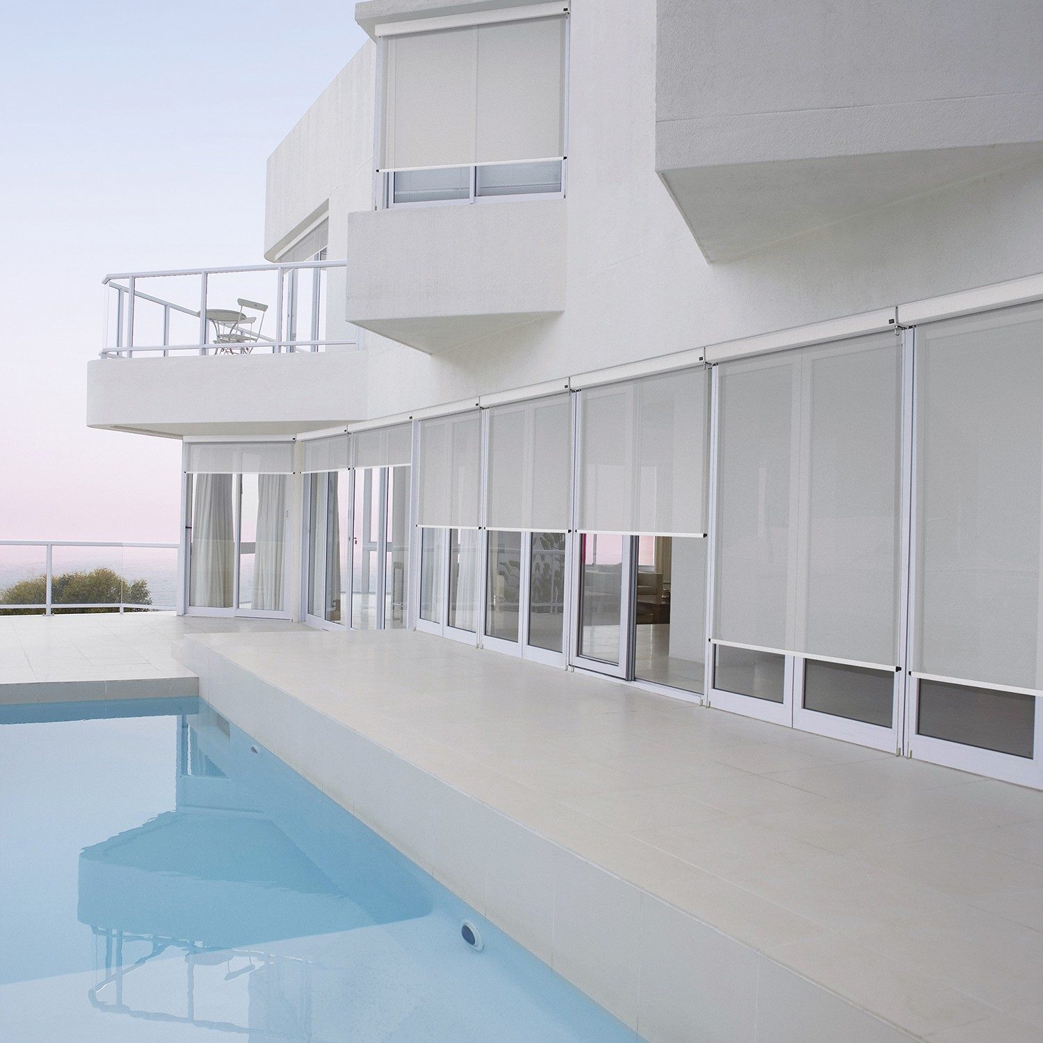 white exterior house with alpha drop screens beside a pool